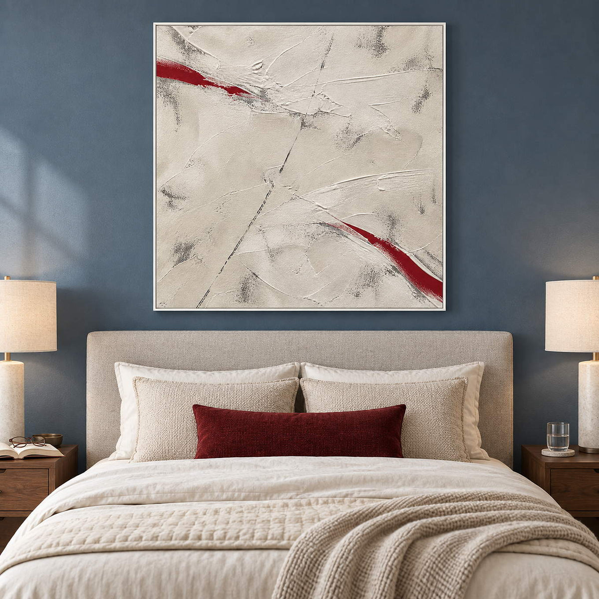 Ivory textured abstract painting with red diagonal strokes in a white frame in a bedroom.