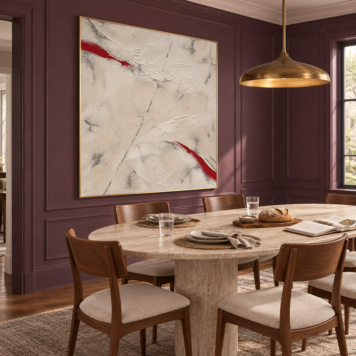 Ivory textured abstract painting with red diagonal strokes in a gold frame in a dining room.