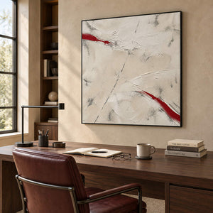 Ivory textured abstract painting with red diagonal strokes in a black frame in a home office.