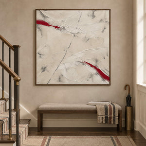 Ivory textured abstract painting with red diagonal strokes in a brown wood frame on a stair landing.