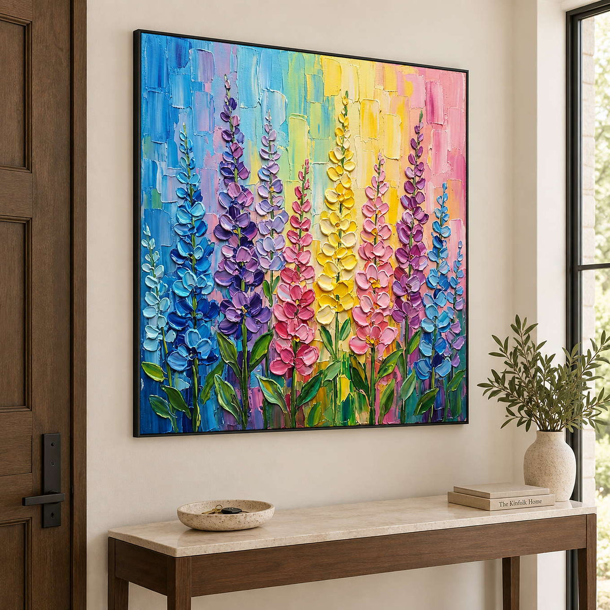Tall purple, pink and yellow flowers against a bright pastel background in a black frame, displayed above an entryway console.