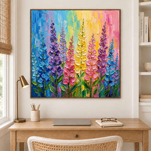 Tall purple, pink and yellow flowers against a bright pastel background in a brown wood frame, displayed in a home office.