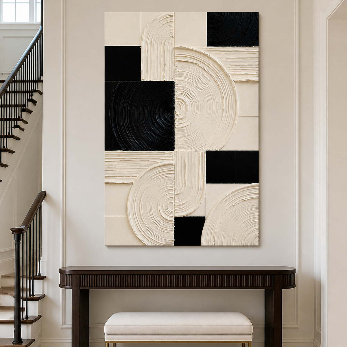 Frameless cream and black artwork above a console beside a staircase.