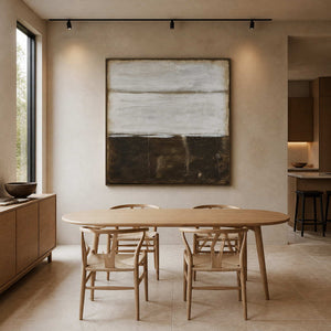 Wood-framed earth-toned abstract above an oval dining table with woven wooden chairs.