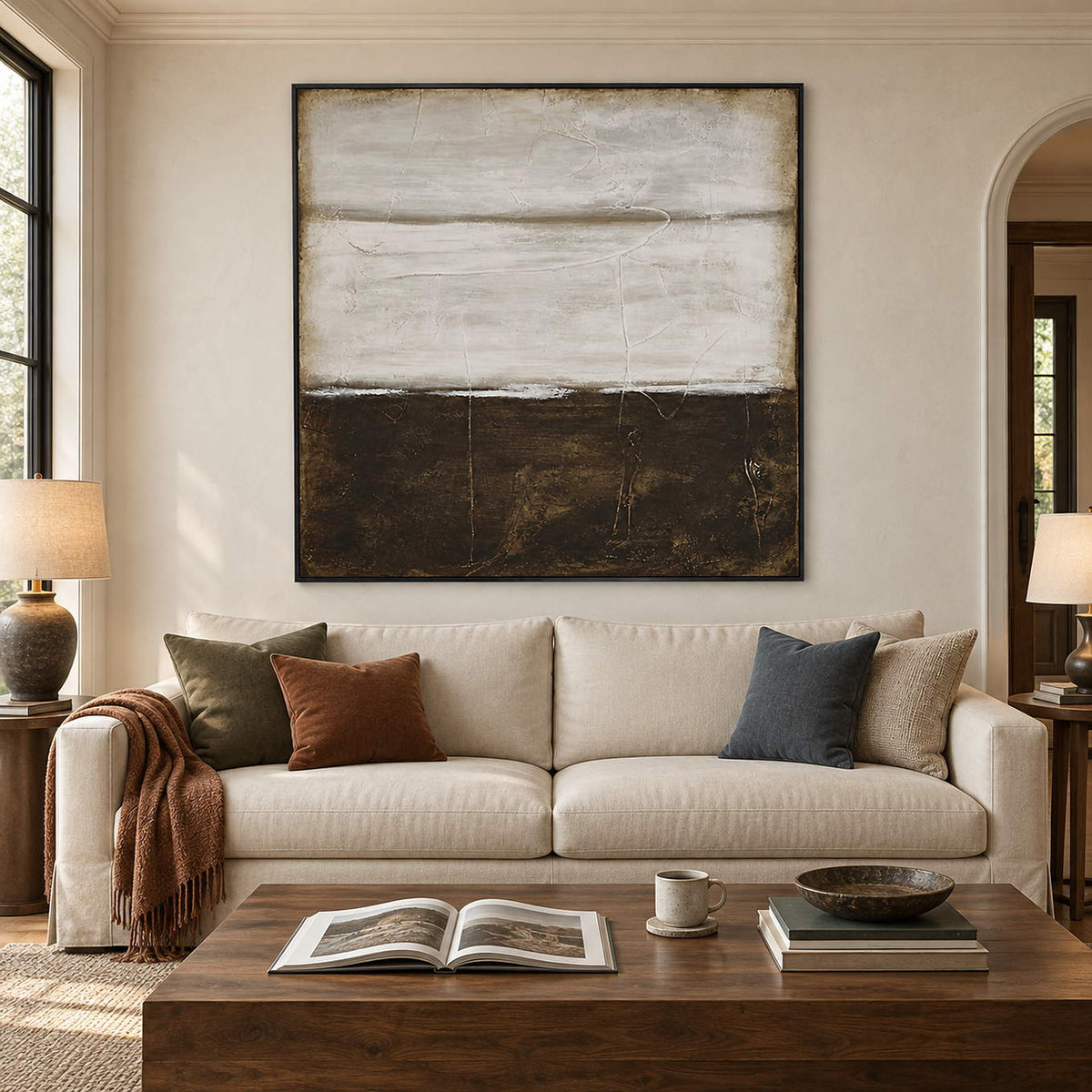 Square abstract painting with pale gray layers above a dark brown field in a black frame in a living room.