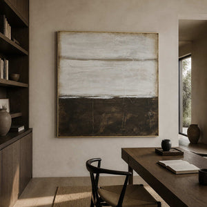 Gold-framed pale gray and brown abstract above a wooden study desk beside bookshelves.