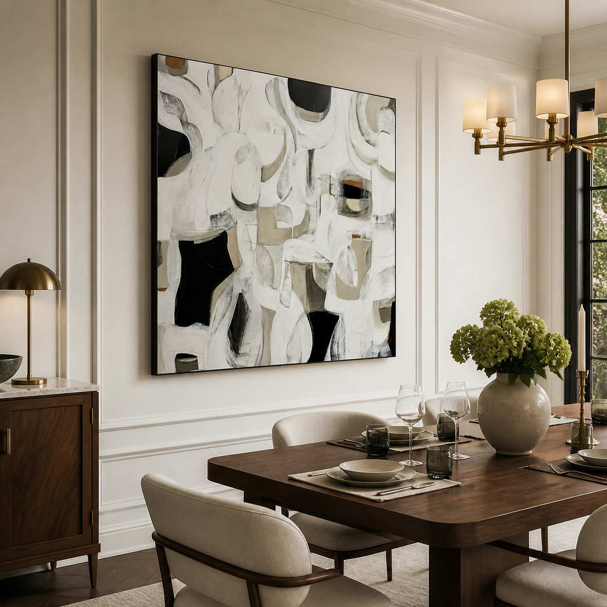 Black framed abstract artwork beside a wooden dining table set with wine glasses.