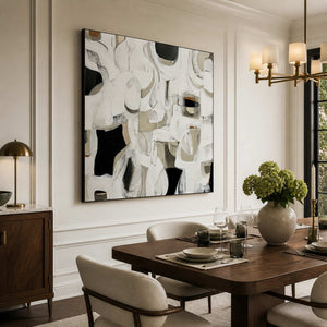 Black framed abstract artwork beside a wooden dining table set with wine glasses.