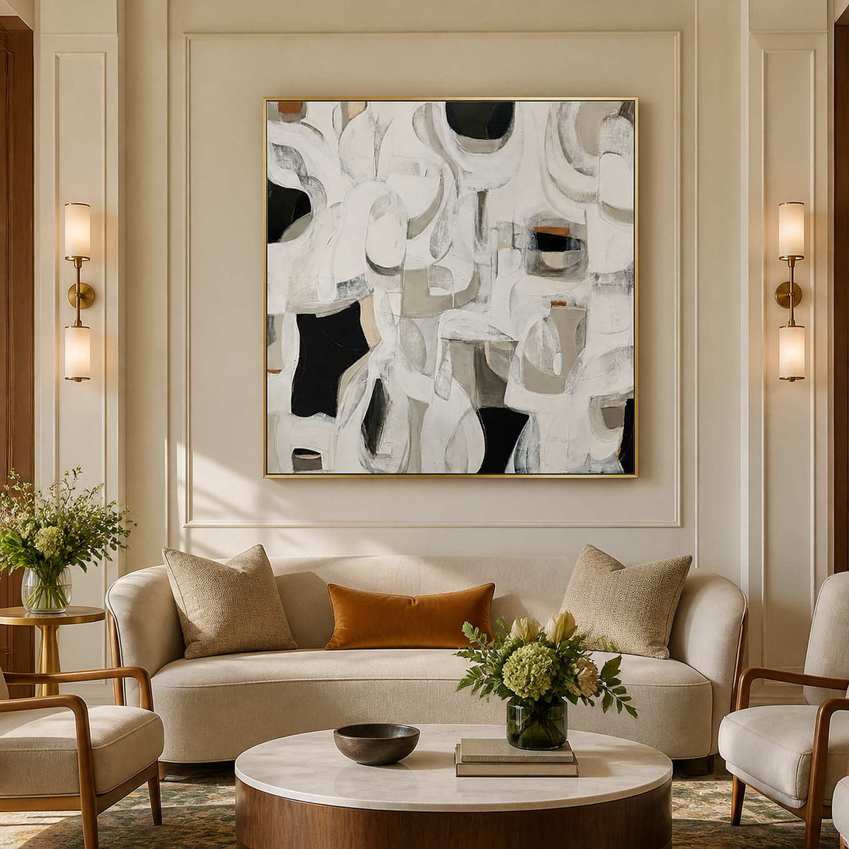 Gold framed square abstract artwork above curved cream seating in a hotel lounge.