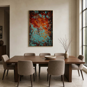 Gold framed turquoise and orange textured painting beside a wooden dining table.