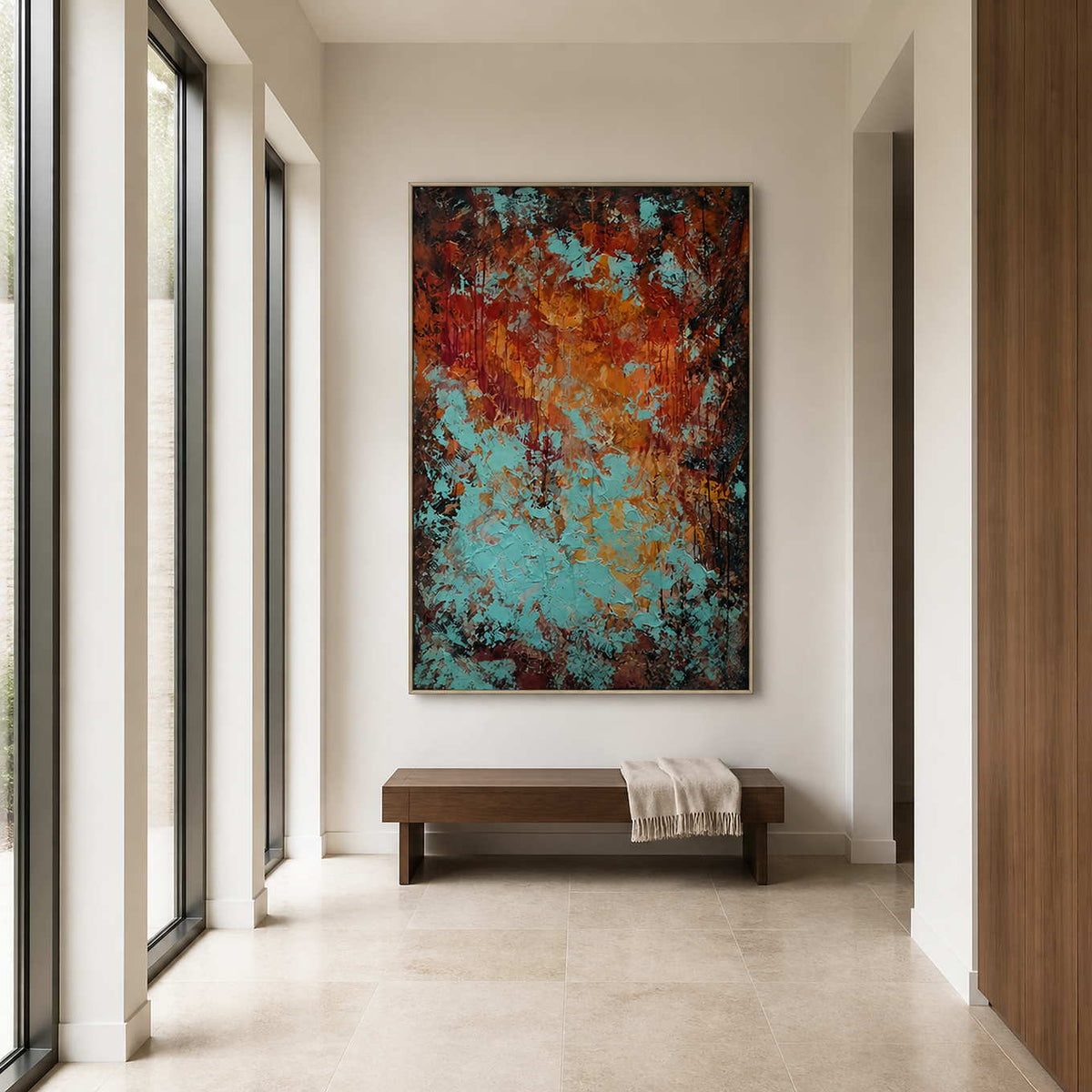 Silver framed rust and turquoise abstract painting above a bench in a bright hallway.