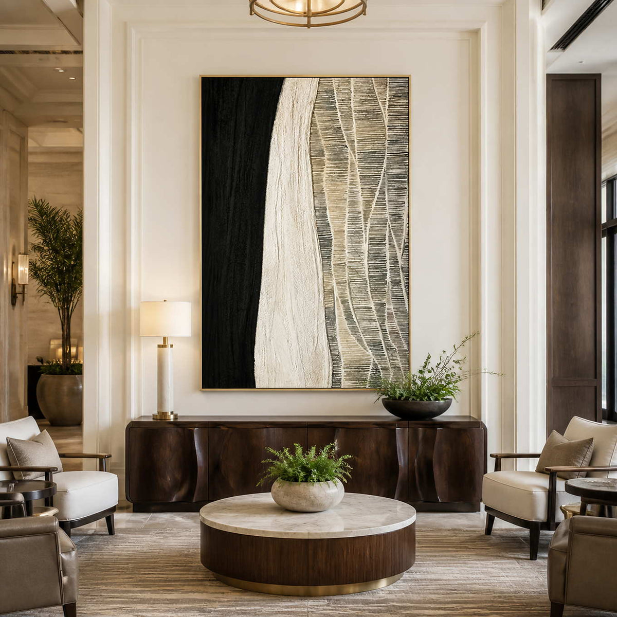 Gold framed black and cream artwork above a cabinet between hotel lounge chairs.