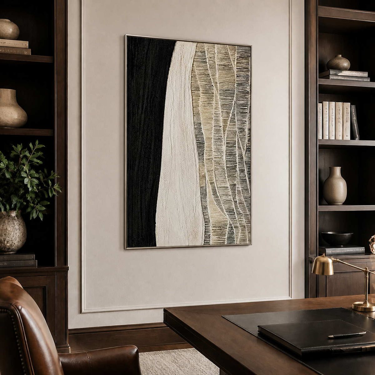 Silver framed woven abstract artwork between dark bookshelves above a wooden study desk.