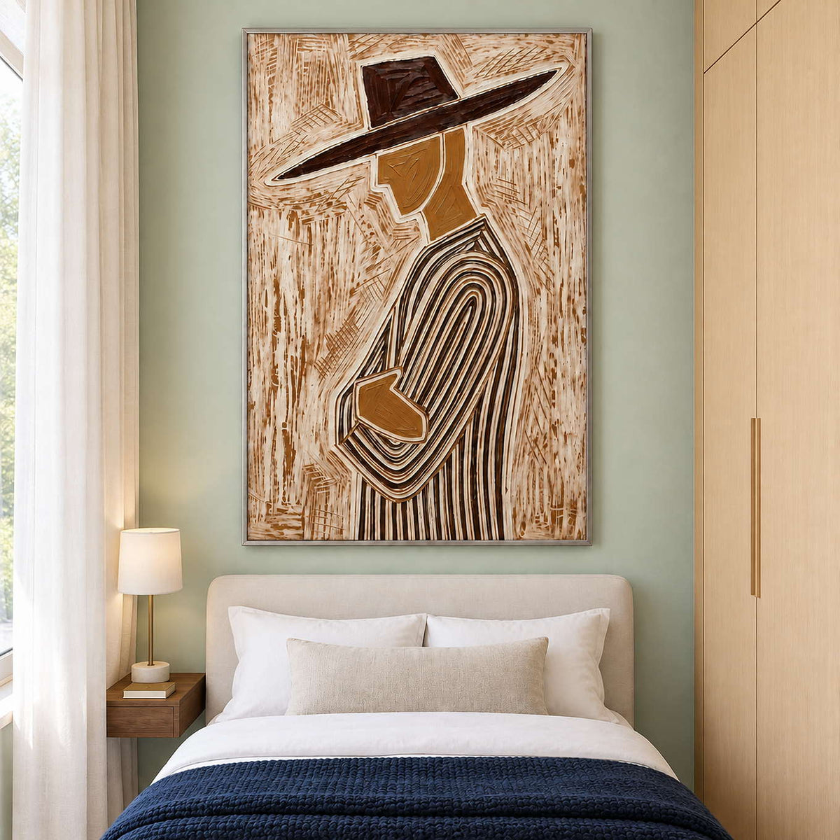 Tall profile artwork above a cream bed with navy throw on a pale green wall.