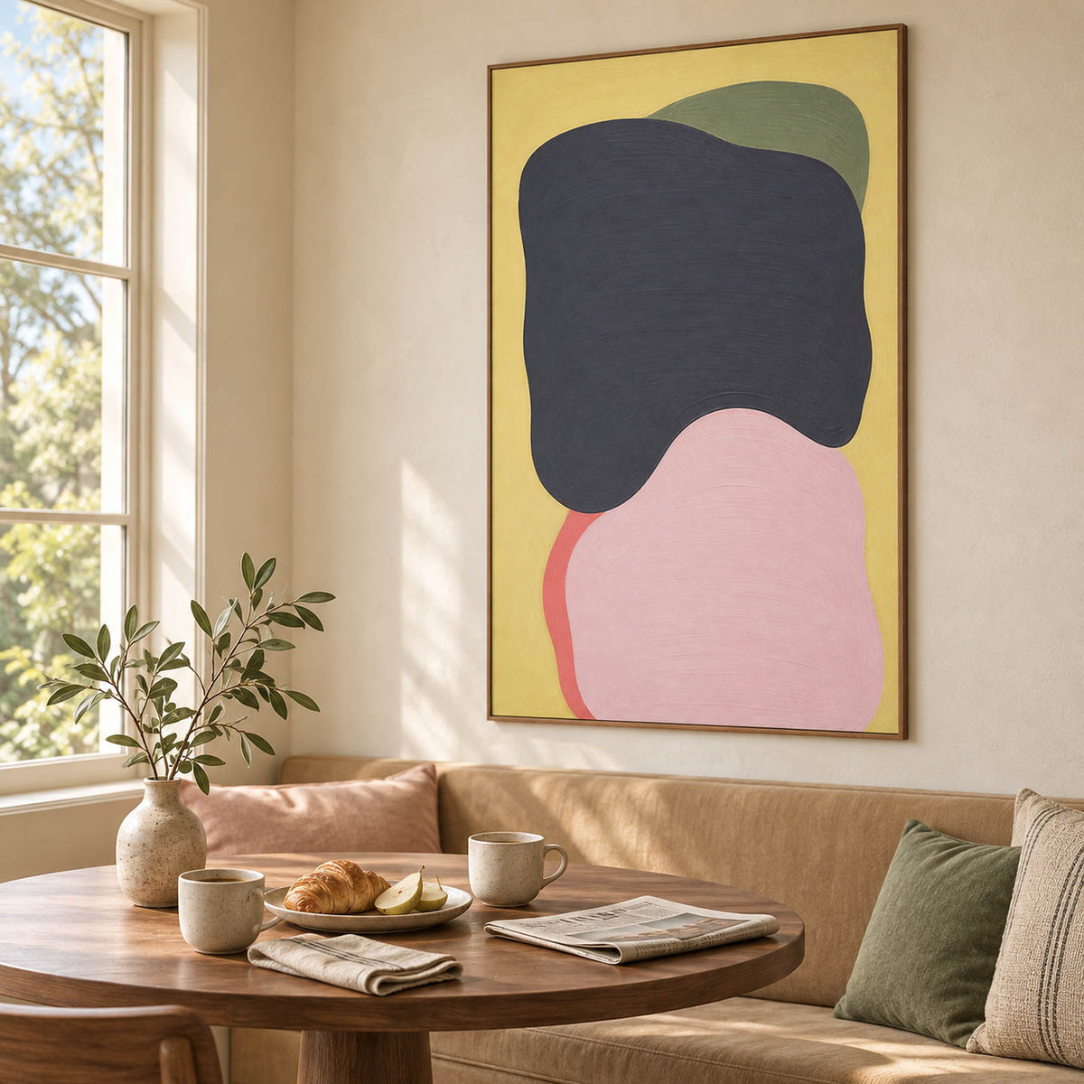 Yellow abstract painting with charcoal, blush, olive, and coral shapes in a brown wood frame in a breakfast dining area.