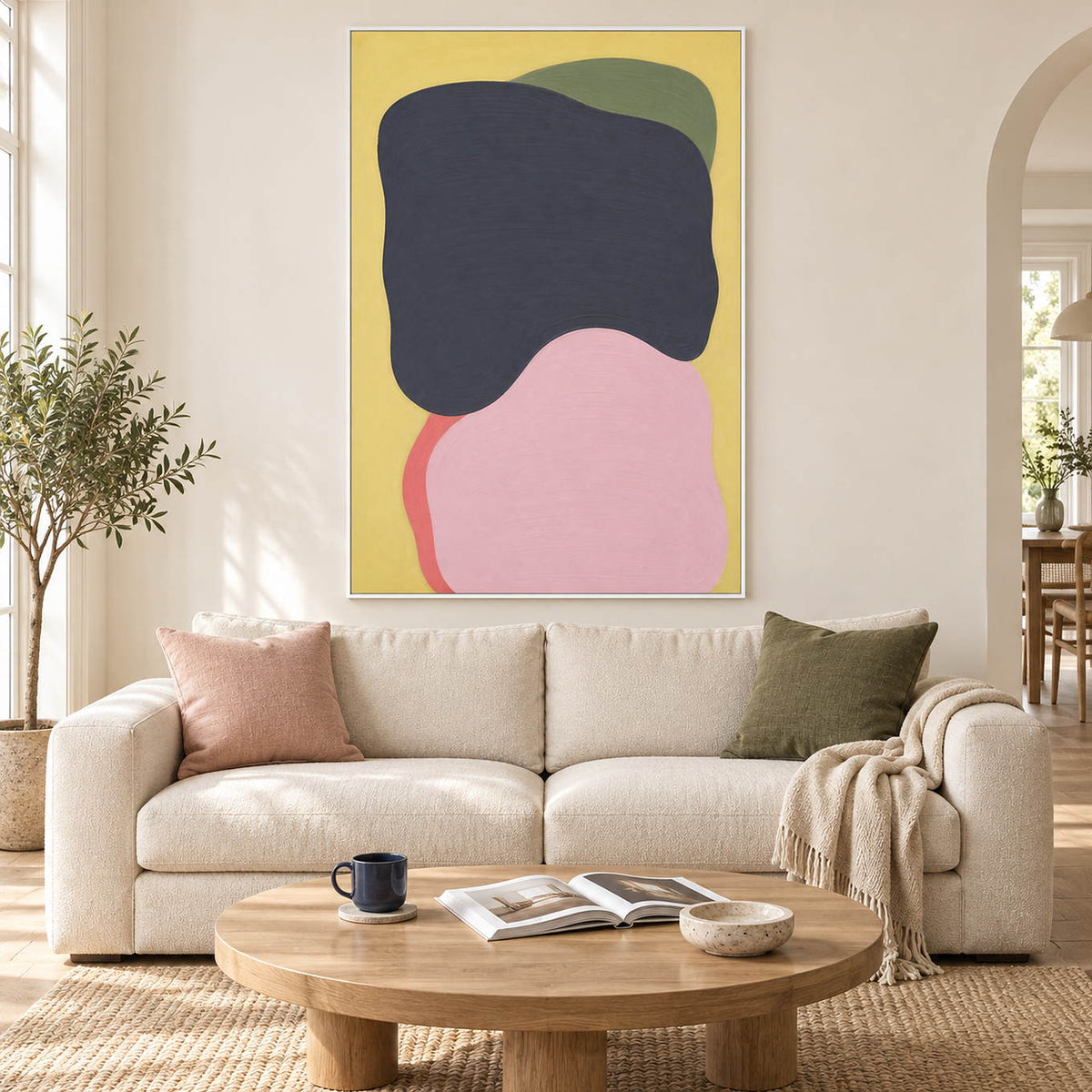 Yellow abstract painting with charcoal, blush, olive, and coral shapes in a white frame in a living room.