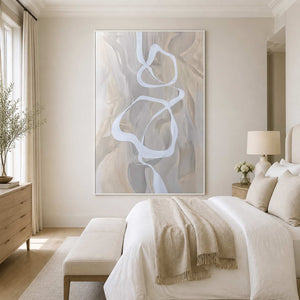 White framed flowing abstract artwork beside a neutral bed in a bright contemporary bedroom.