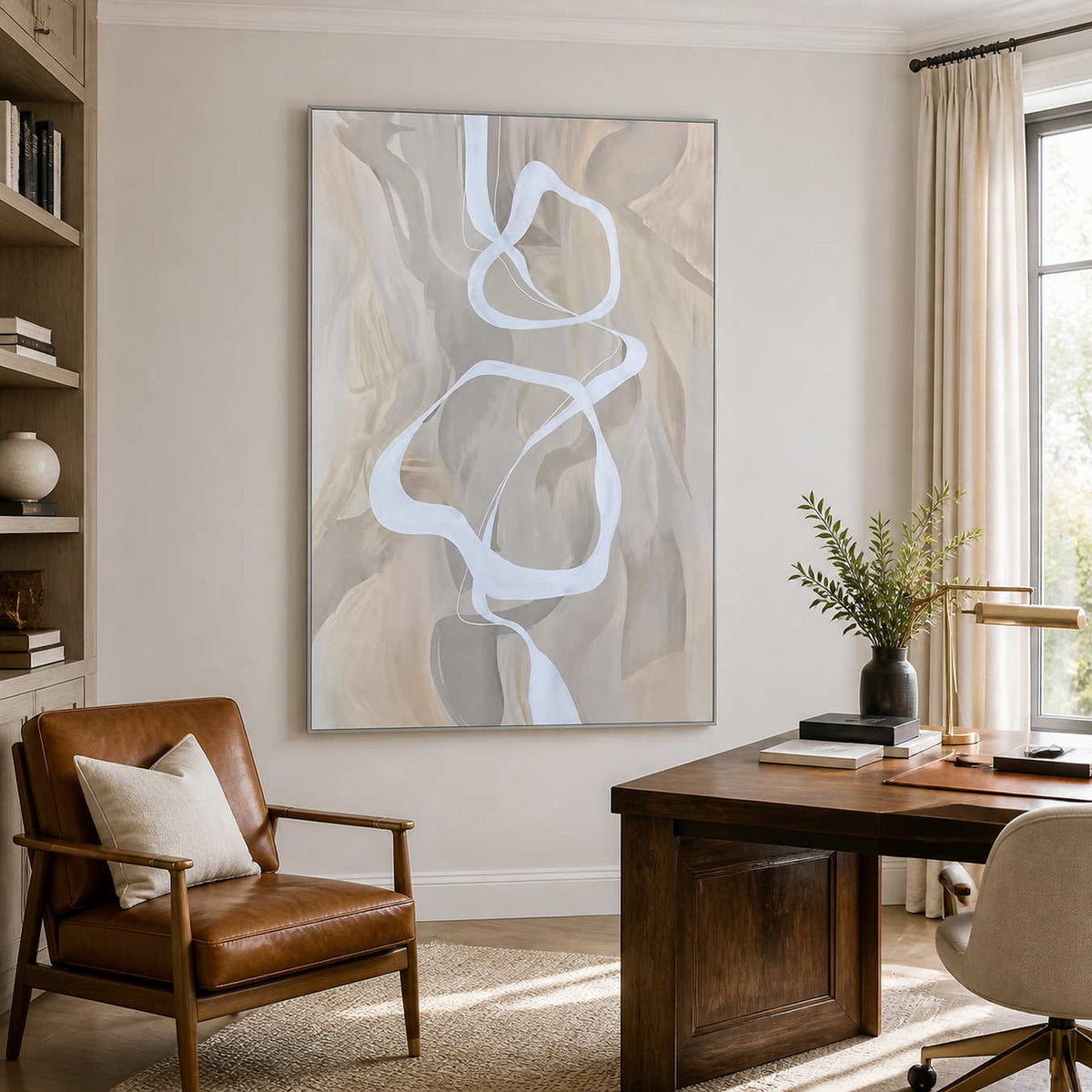 Silver framed ribbon abstract artwork between a leather reading chair and wooden office desk.