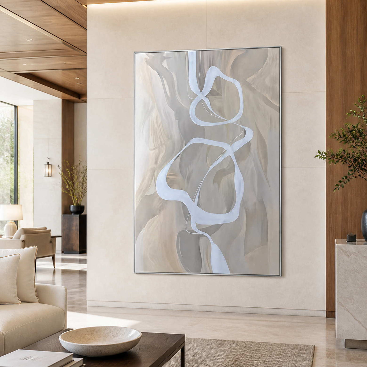 Silver framed flowing abstract artwork on a stone wall beside refined hotel lounge seating.