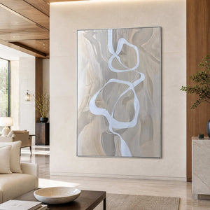 Silver framed flowing abstract artwork on a stone wall beside refined hotel lounge seating.