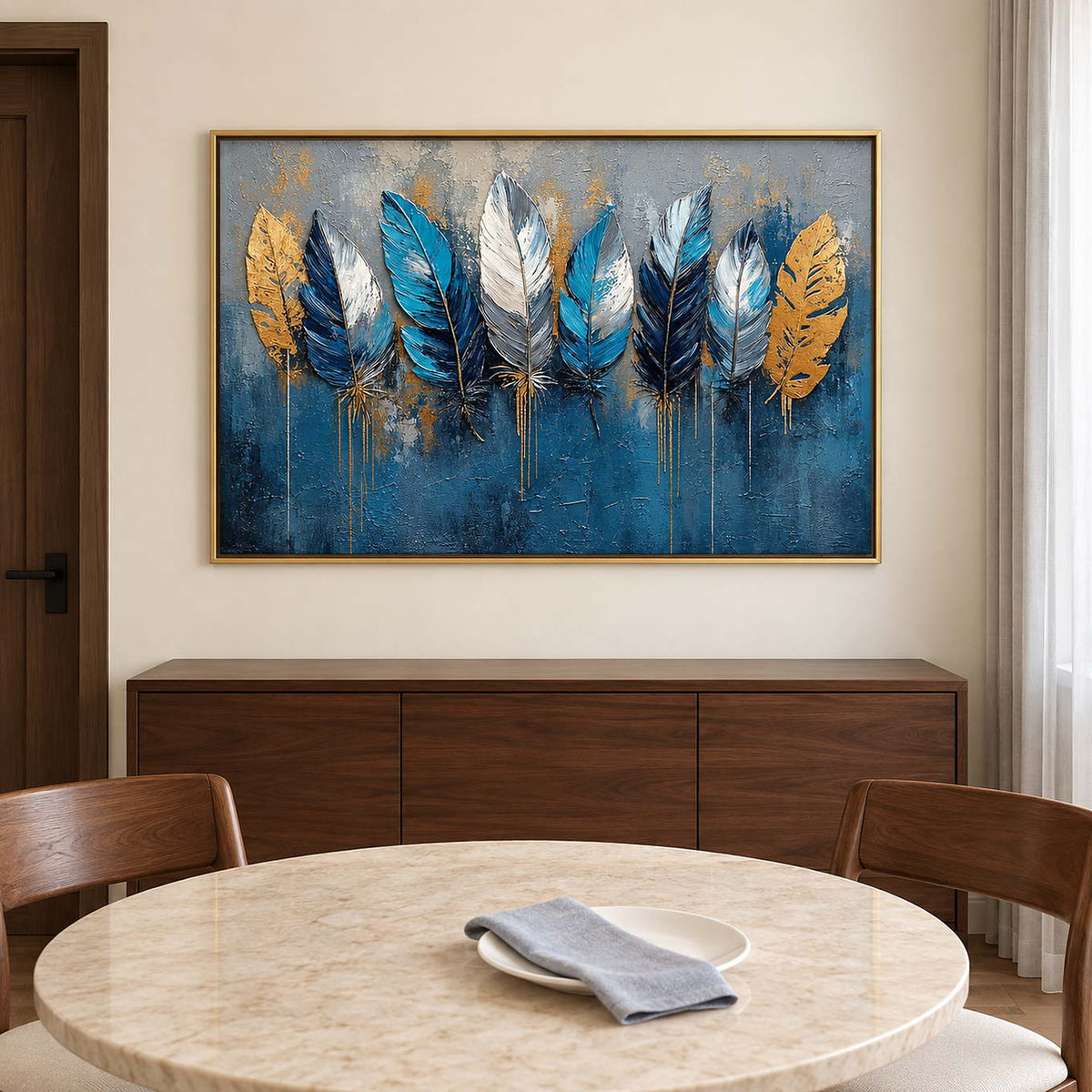 Blue, white and gold feathers against a deep blue and gray background in a gold frame, displayed above a dining table.