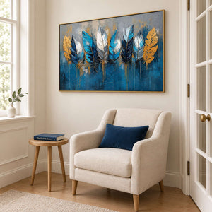 Blue, white and gold feathers against a deep blue and gray background in a gold frame, displayed beside seating in a lounge.