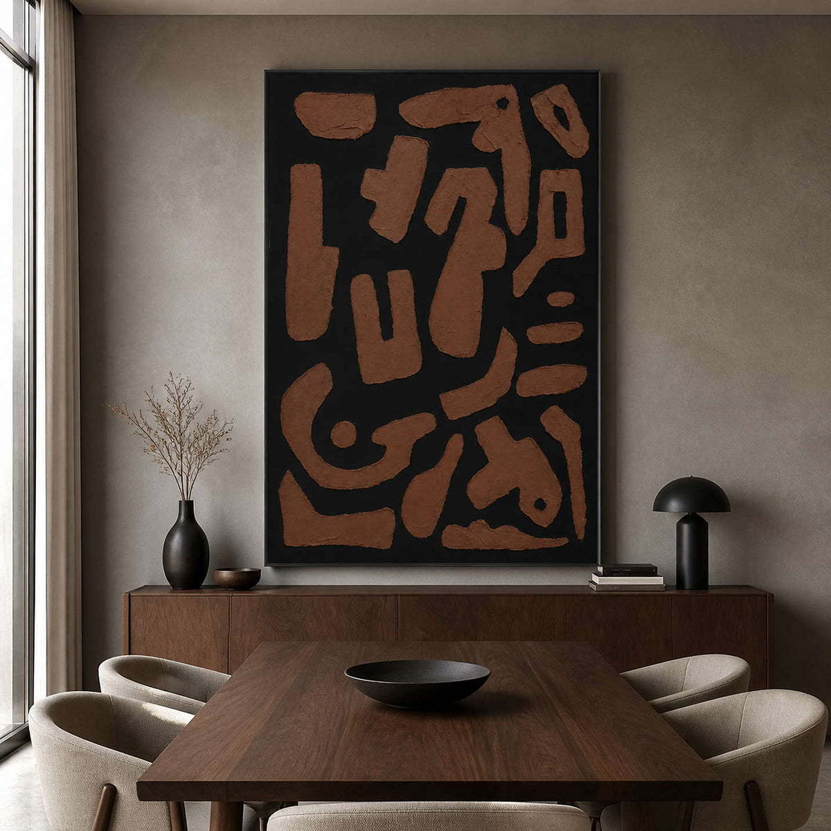 Black framed earthy abstract painting beside a wooden dining table.