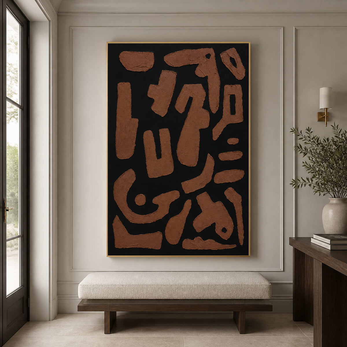 Gold framed rust brown abstract artwork above a cushioned bench in an entryway.