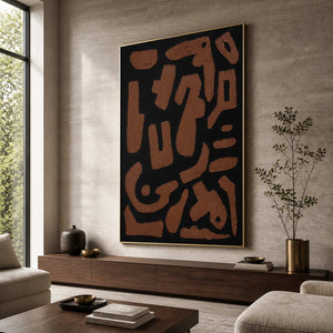 Gold framed rust and black abstract painting beside seating in a sunlit living room.