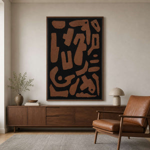 Wood framed rust and black painting beside a leather reading chair.