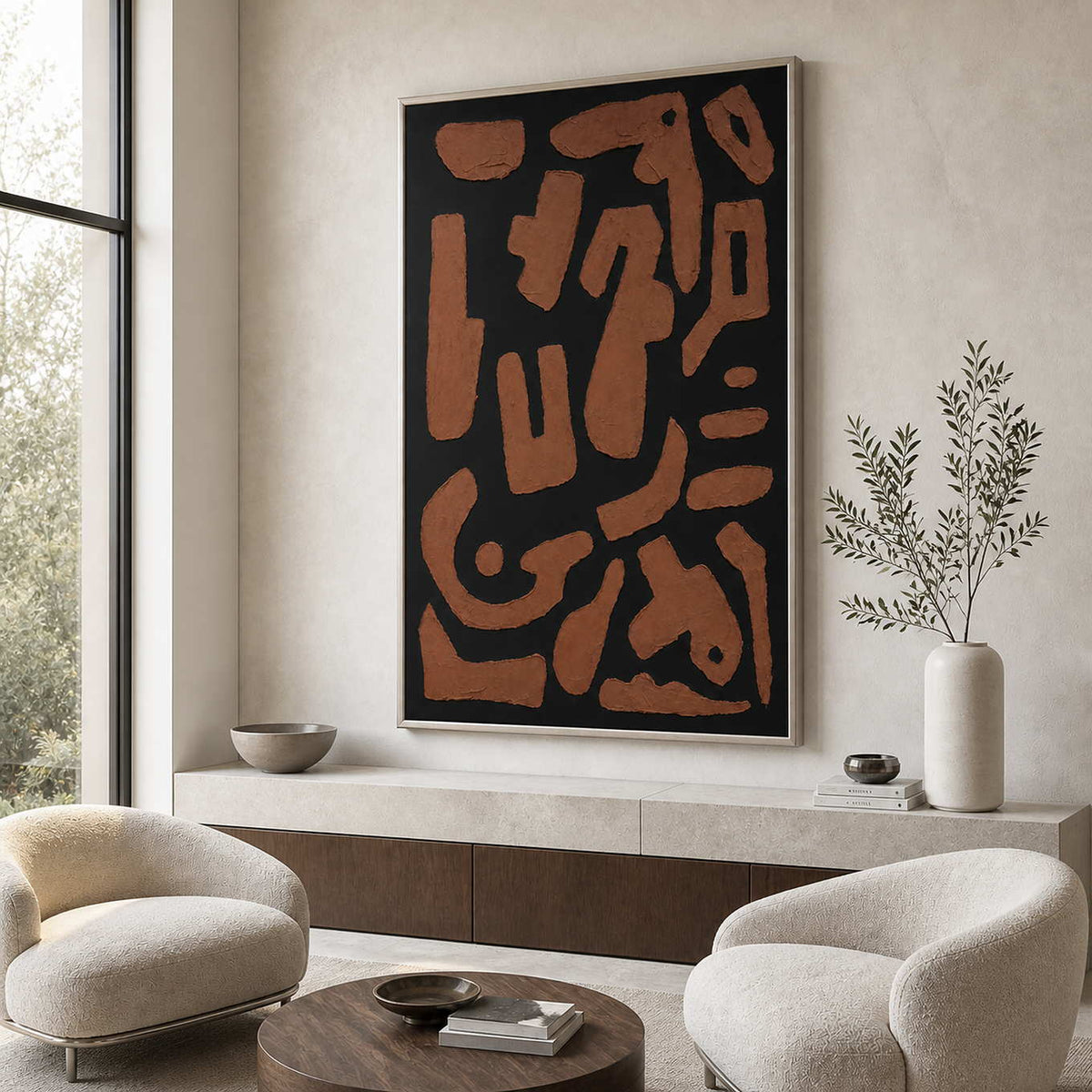 Silver framed rust brown abstract artwork above pale chairs in a sitting room.