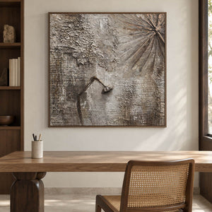 In a study with a desk, an artwork with a brown wood-look frame shows gray-beige grid textures, radiating grooves and a dark bent raised line.