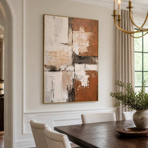 Gold-framed textured abstract wall art beside a wooden dining table and cream chairs.