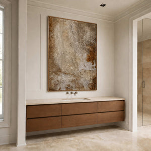 Wood framed weathered abstract artwork above a light stone vanity in a bathroom.