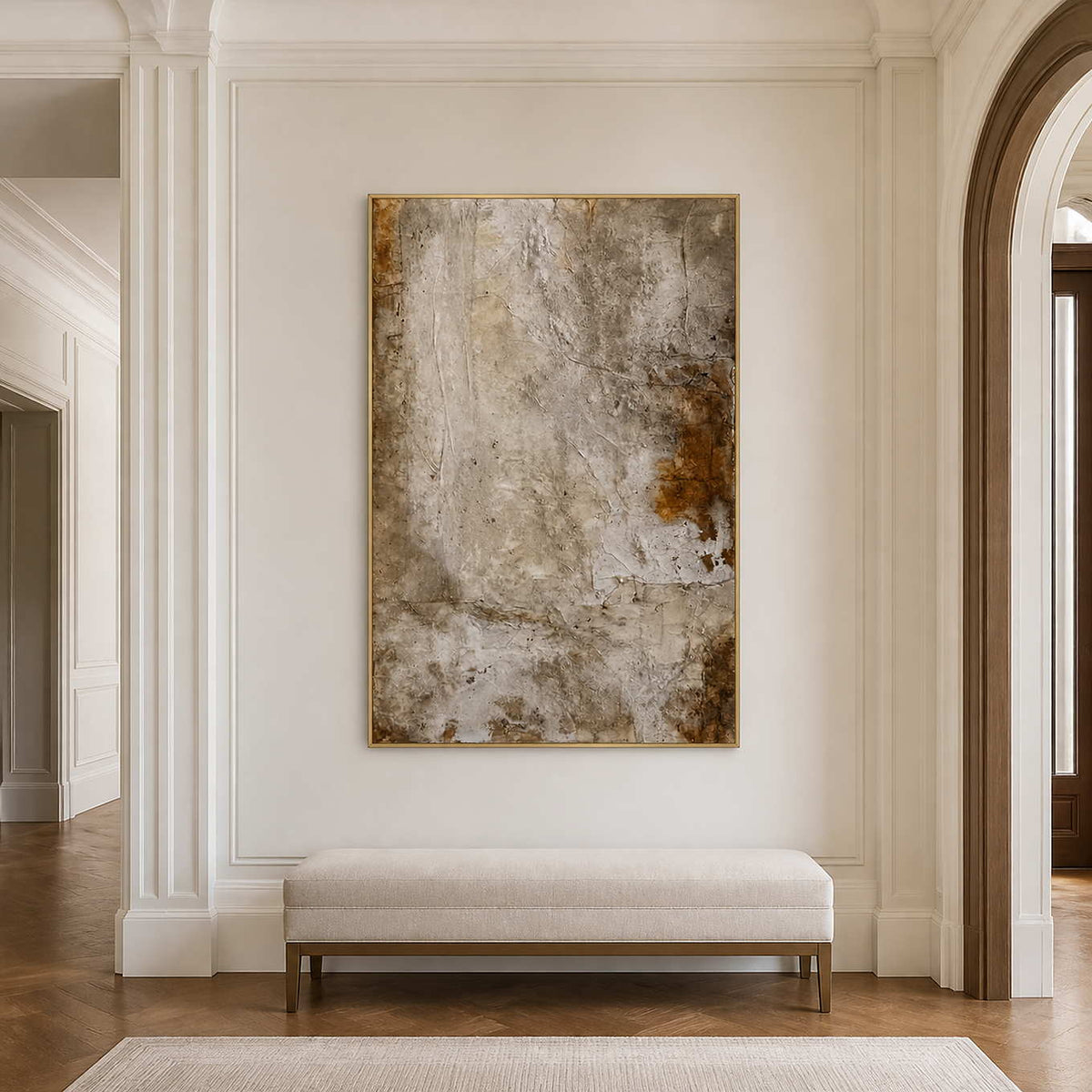 Gold framed earthy abstract artwork above a pale upholstered hallway bench.