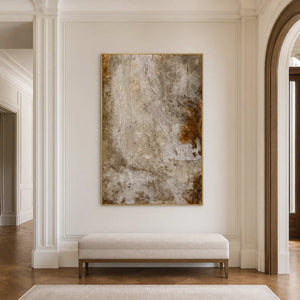 Gold framed earthy abstract artwork above a pale upholstered hallway bench.