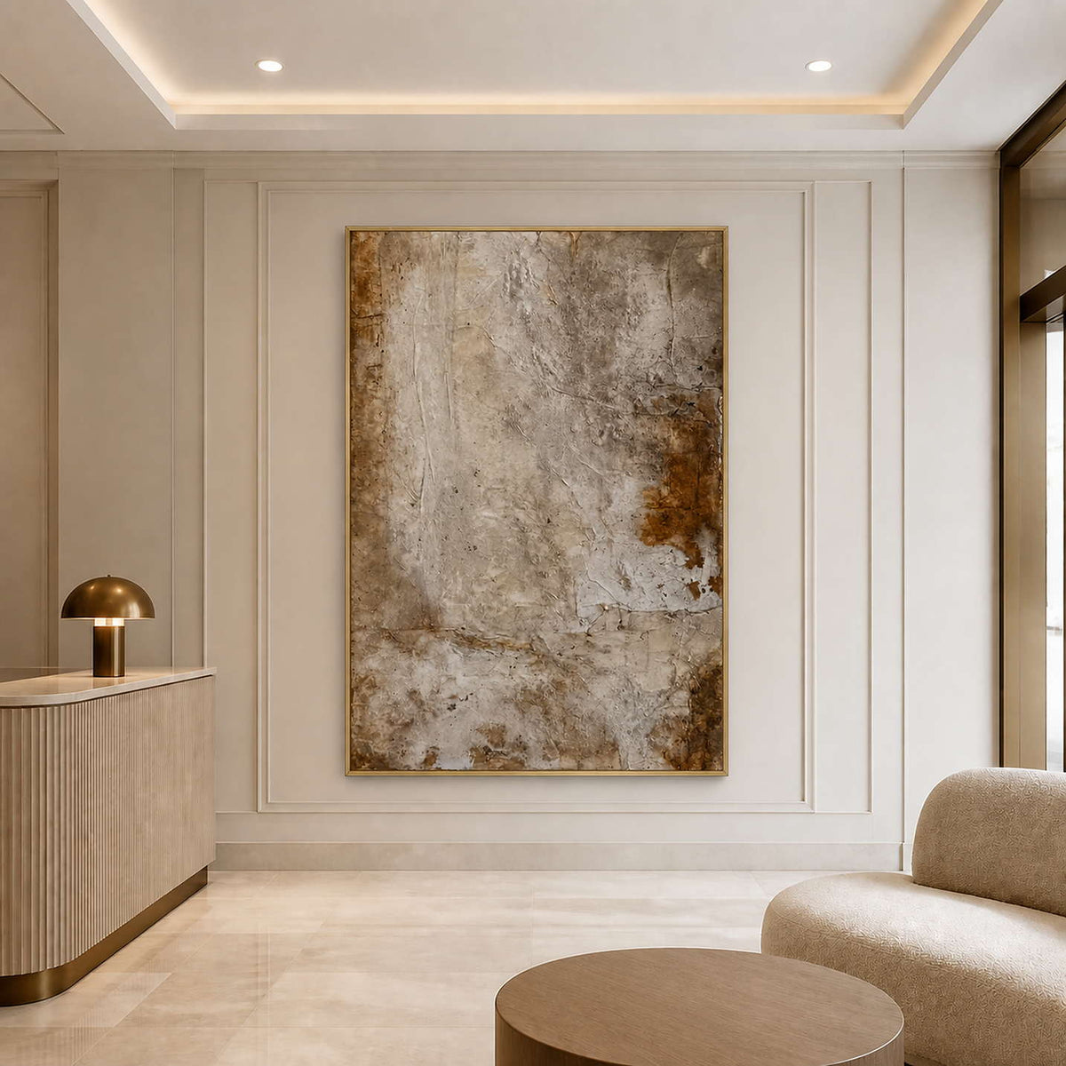 Gold framed warm neutral abstract artwork beside seating in a refined hotel lobby.