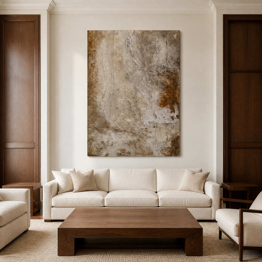 Frameless weathered abstract artwork above a cream sofa between dark wood wall panels.