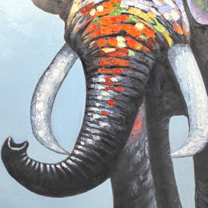 Close-up of the upcurled dark trunk, pale tusks and orange, white and green color blocks.