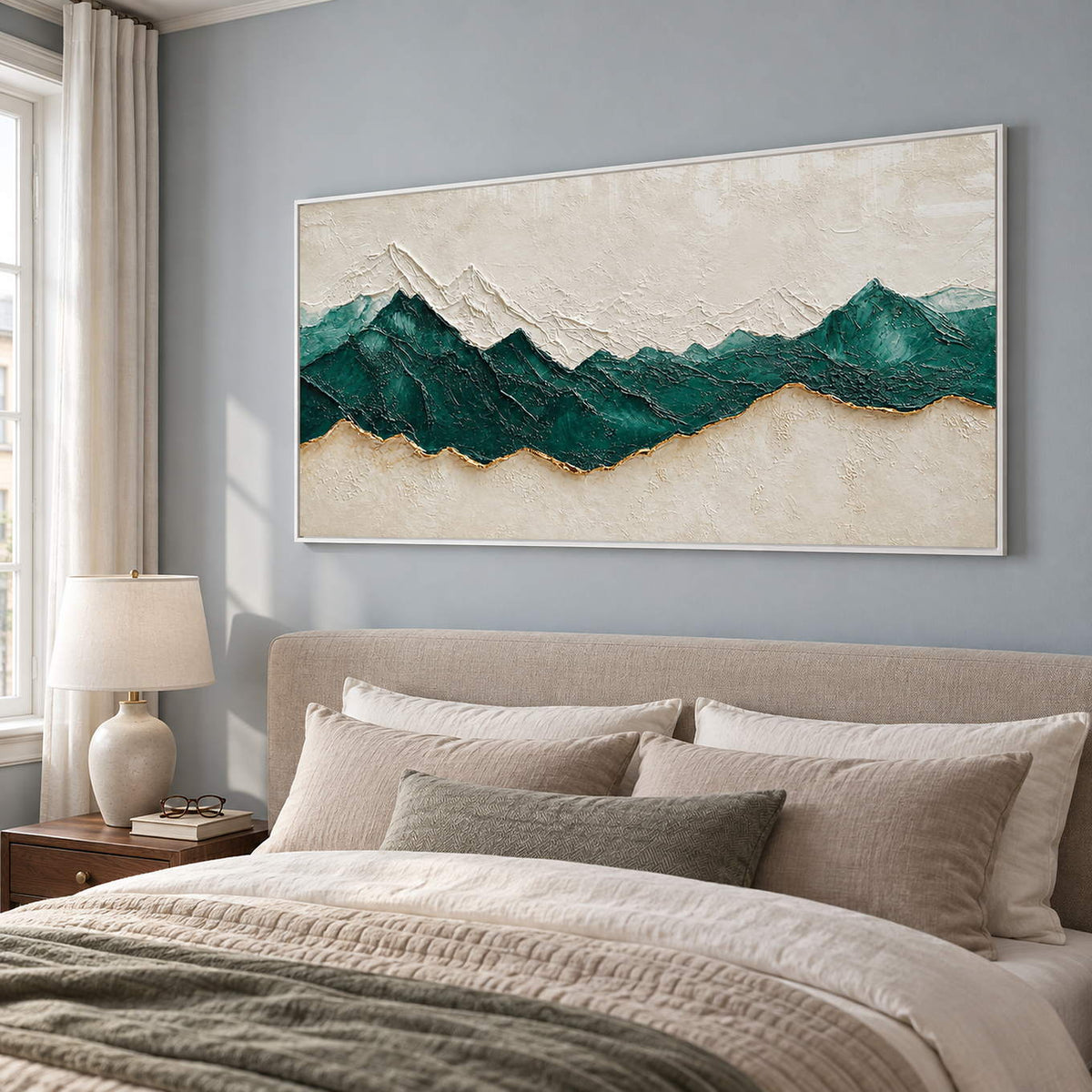Hand-painted panoramic mountain wall art in emerald green, ivory, and gold, displayed in a bedroom in a white frame.