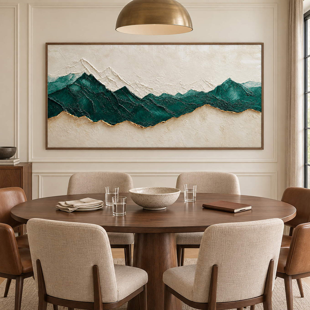 Hand-painted panoramic mountain wall art in emerald green, ivory, and gold, displayed in a dining room in a brown wood frame.