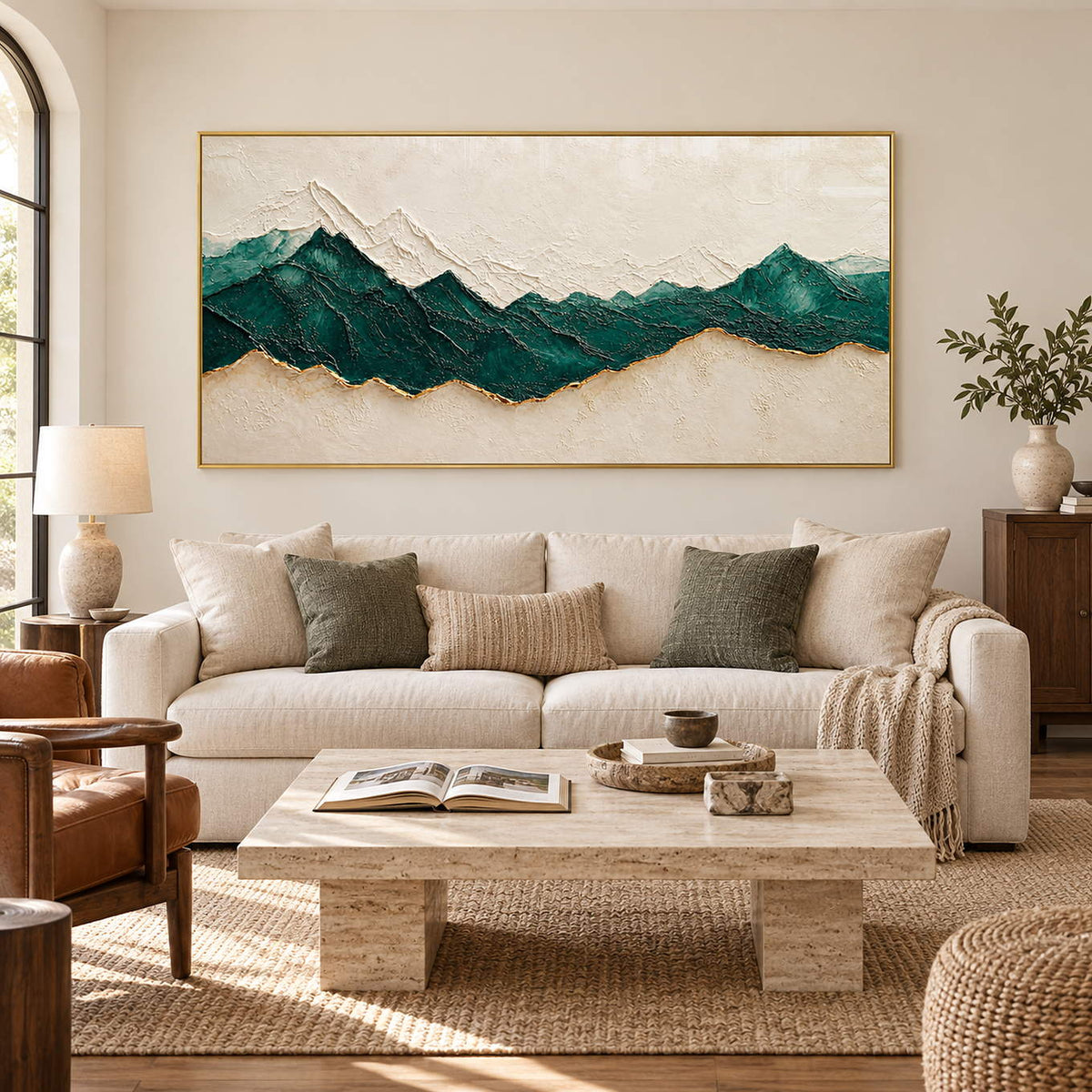Hand-painted panoramic mountain wall art in emerald green, ivory, and gold, displayed in a living room in a gold frame.