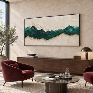 Hand-painted panoramic mountain wall art in emerald green, ivory, and gold, displayed in a reception lounge in a black frame.