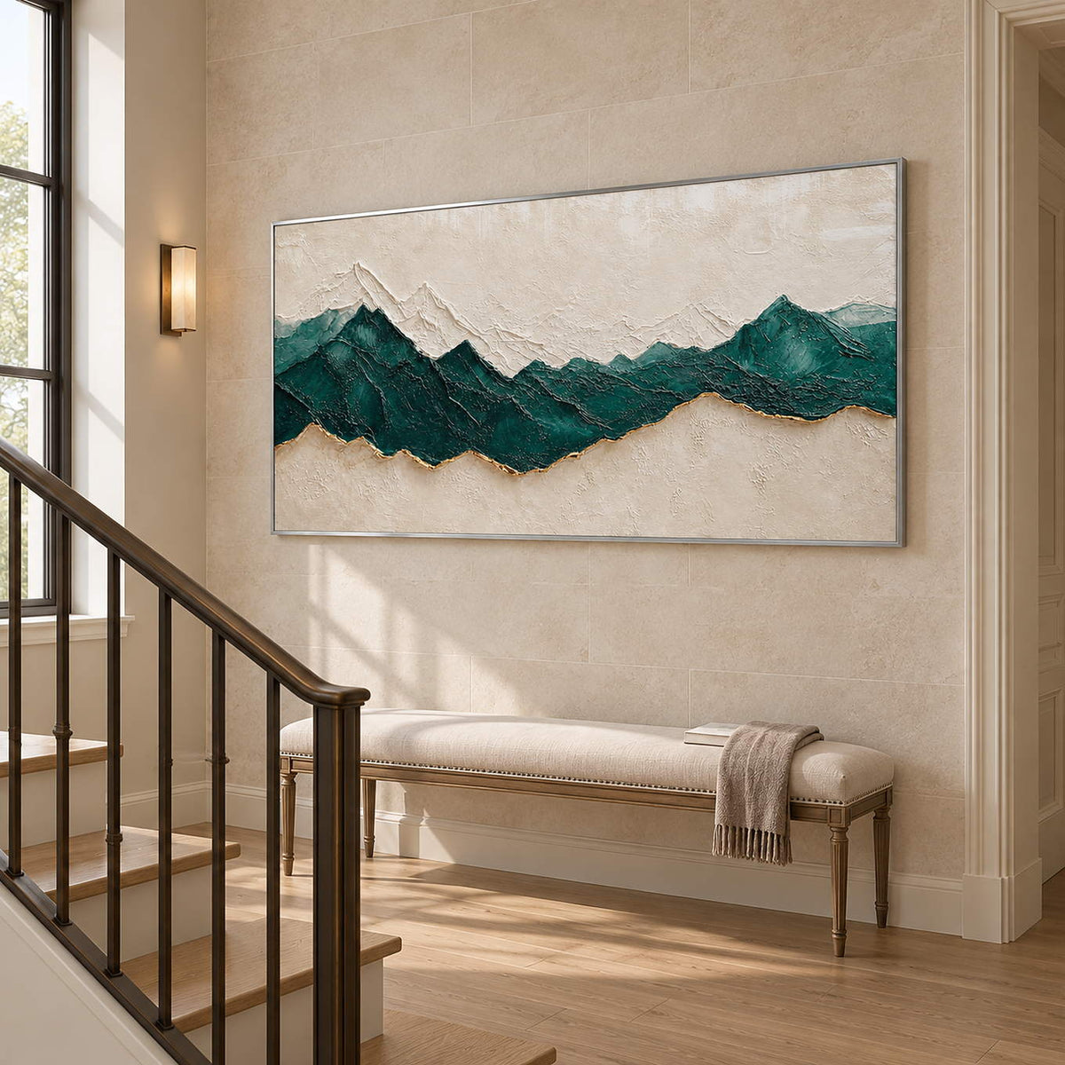Hand-painted panoramic mountain wall art in emerald green, ivory, and gold, displayed beside a staircase in a silver frame.