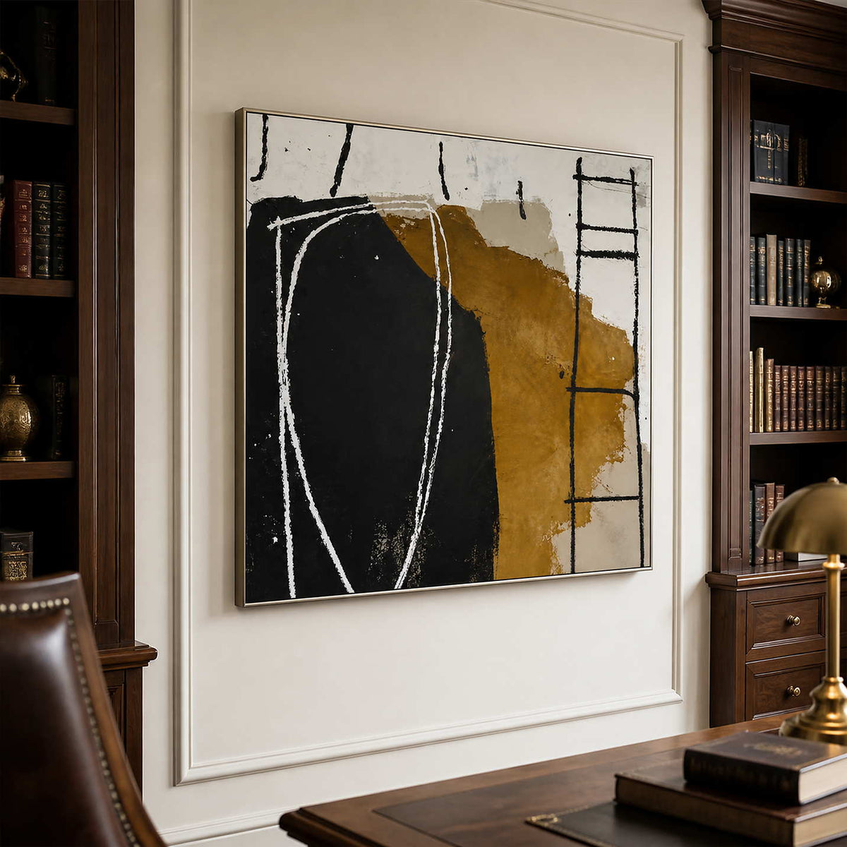 Silver framed abstract painting beside a wooden desk and dark wood bookshelves.