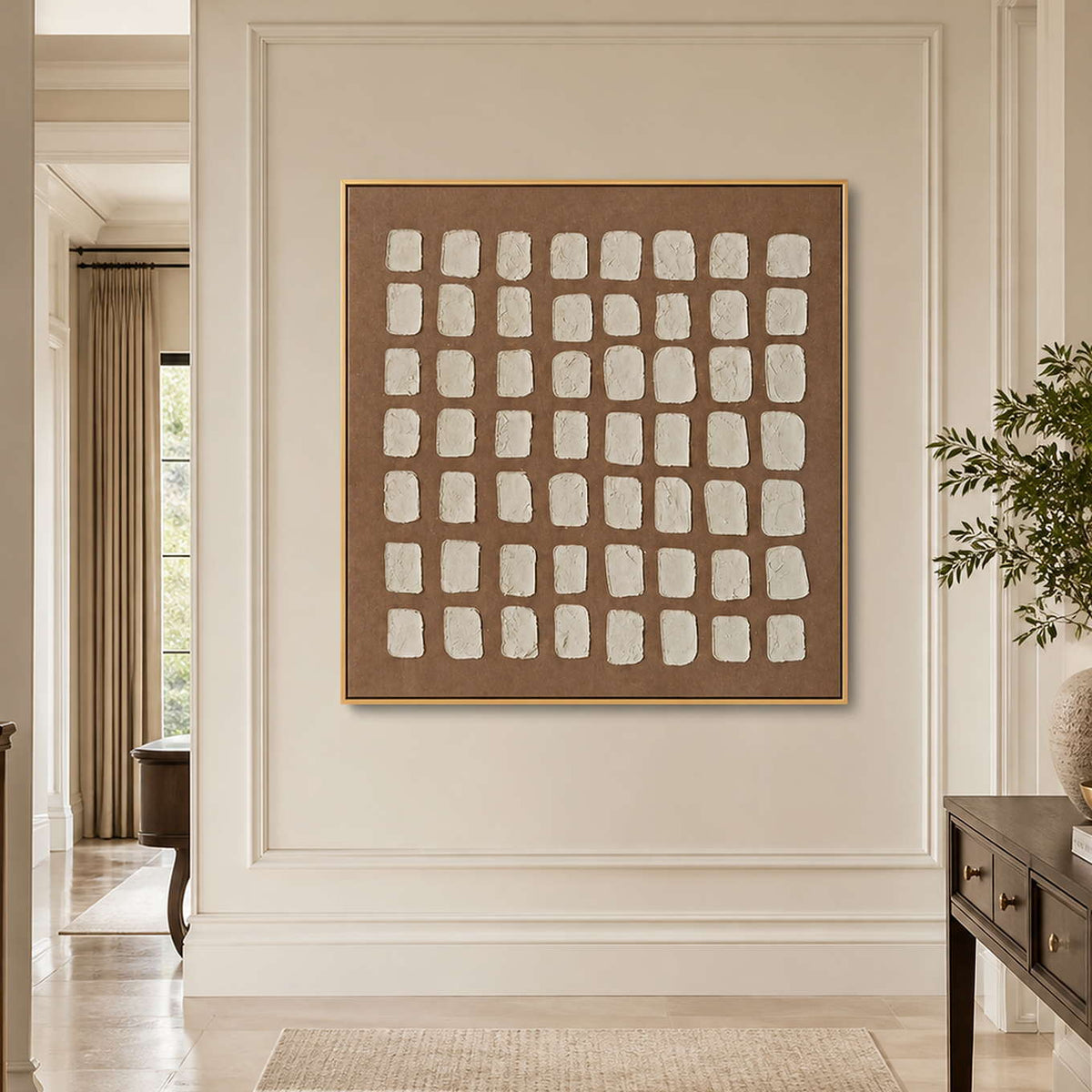 Gold framed cream grid artwork on a hallway wall near an open doorway.