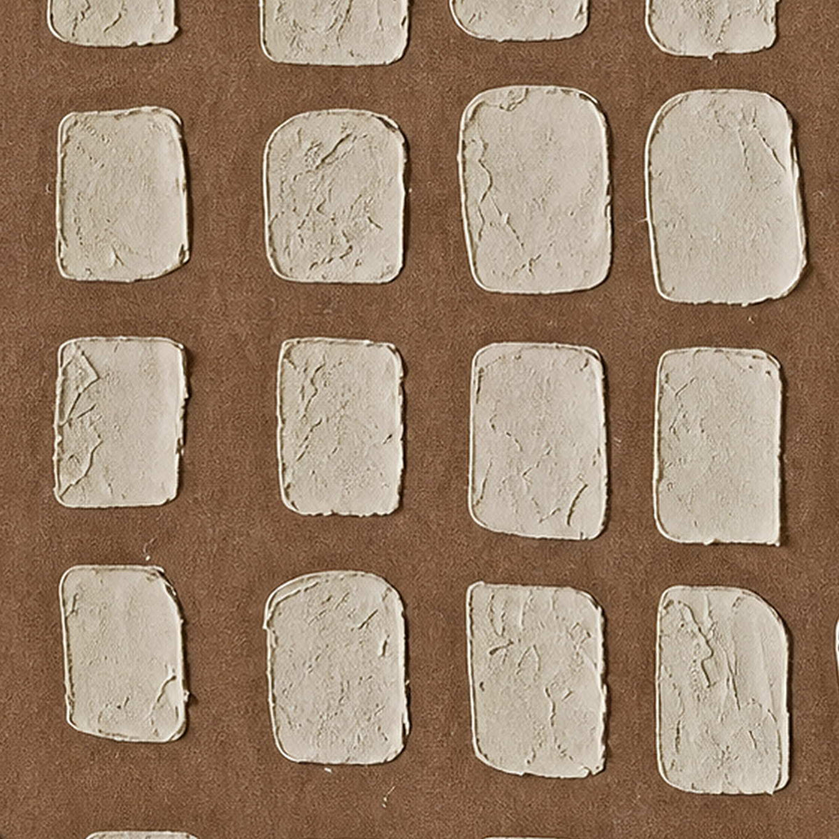 Close view of cracked cream rectangles with rounded corners on a fine brown ground.