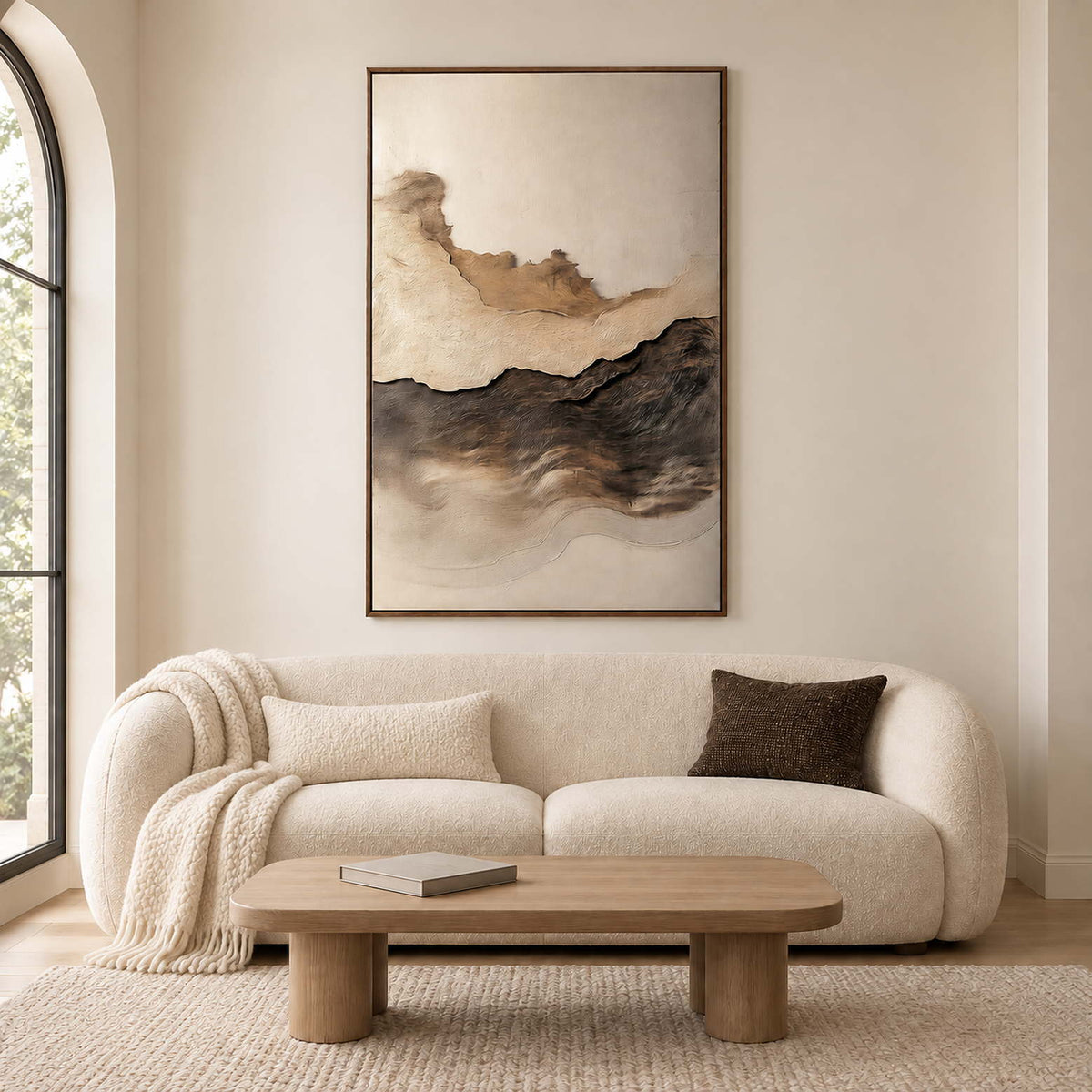 Layered brown and charcoal hills beneath an open ivory sky in a brown wood frame, displayed above a sofa in a living room.