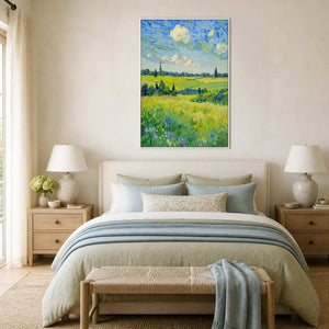 Bright field painting in a white frame above an ivory bed with blue bedding.
