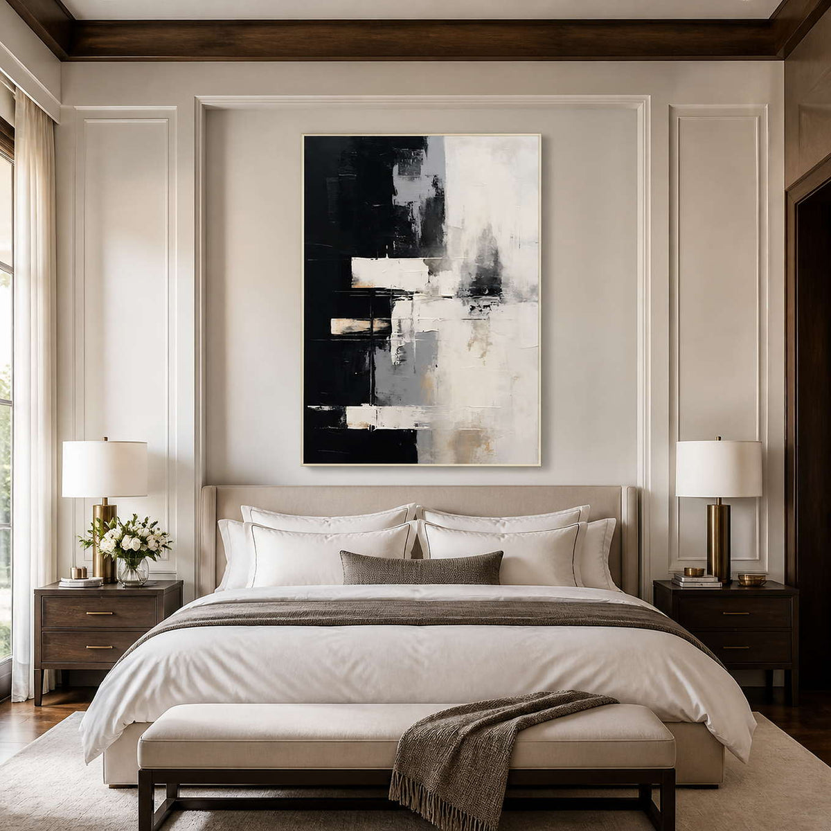White framed black and cream artwork above a neutral bed between matching lamps.